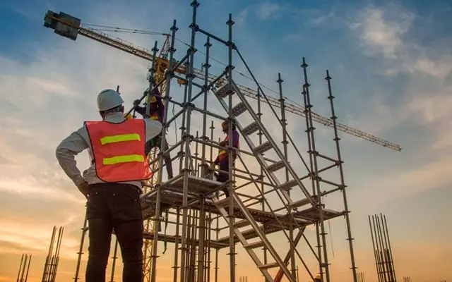 Shows people at the construction site with tubular scaffolding