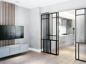 Bilik moden dengan TV dinding yang dipasang pada panel kayu, bersebelahan dapur bergaya di belakang pintu gelangsar kaca. Tona neutral, hiasan minimalis.
