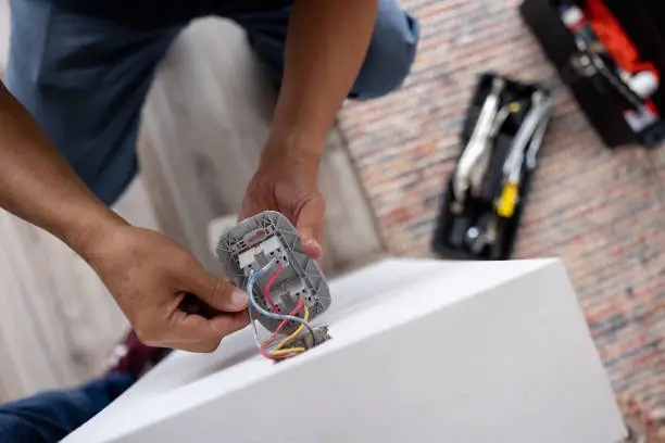 Teknisi profesional sedang menyemak sambungan wiring rumah dengan pemutar skru.