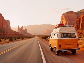Yellow van with luggage parked on a desert road, surrounded by red rock formations at sunset. The scene feels peaceful and adventurous.