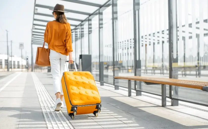 A woman walking down the street with her luggage.
