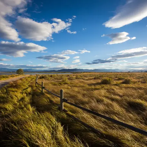 Countryside in Western Montana with beautiful blue sky and fluffy clouds above it.