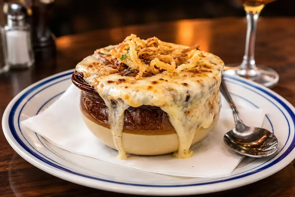 A bowl of soup garnished with cheese, served on a plate with a piece of bread.