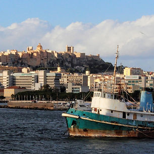 una barca in primo piano e in secondo piano la città di cagliari