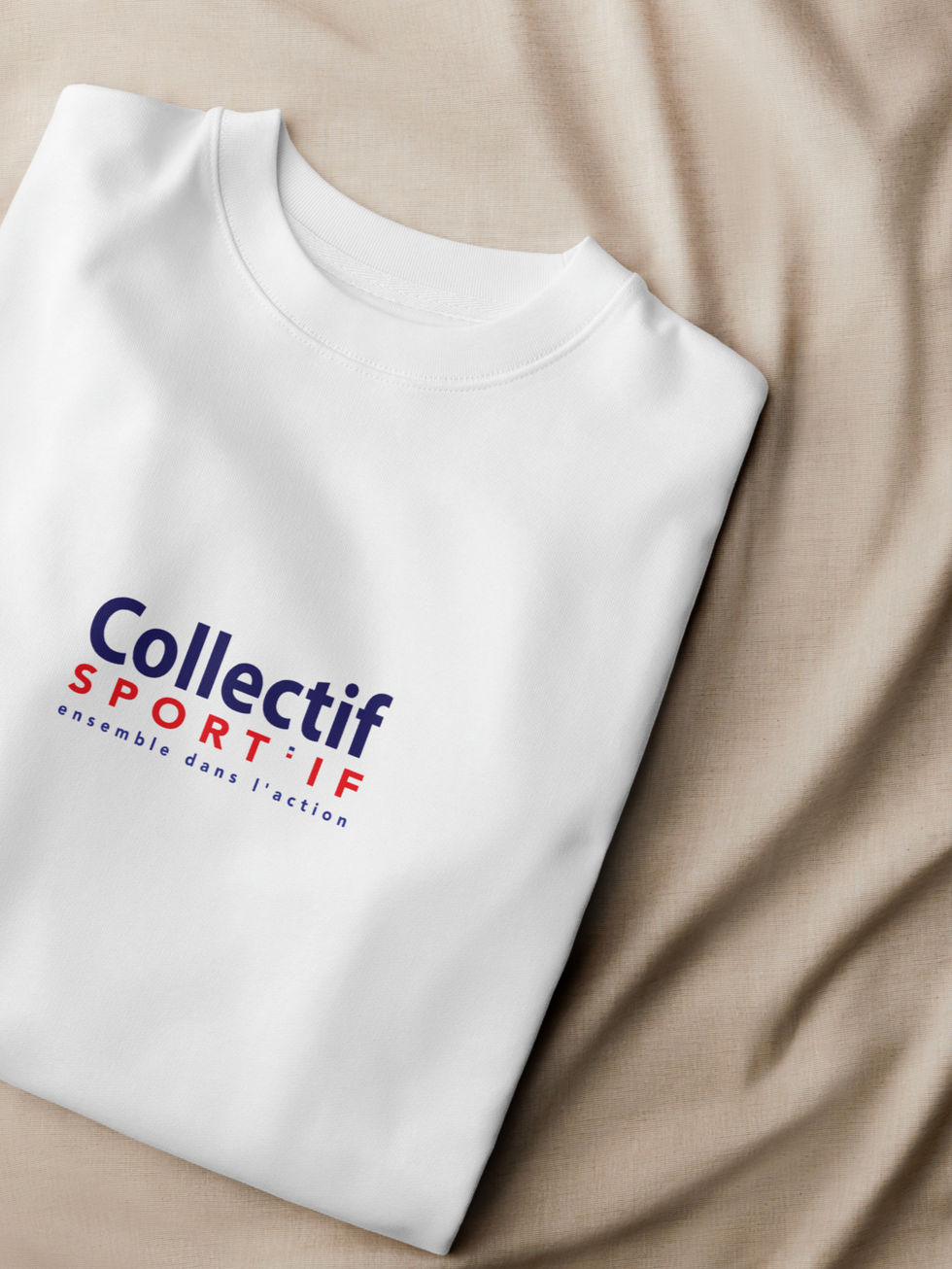 pose sur un drap beige, sweatshirt plié mettant en valeur le logo Collectif Sportif en rouge et bleu milieu devant