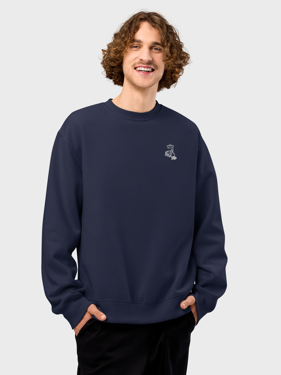 vue de face d'un jeune homme souriant qui porte le sweashirt ras-du-cou bleu amrine avec le logo Mascotte brodé en blanc côté