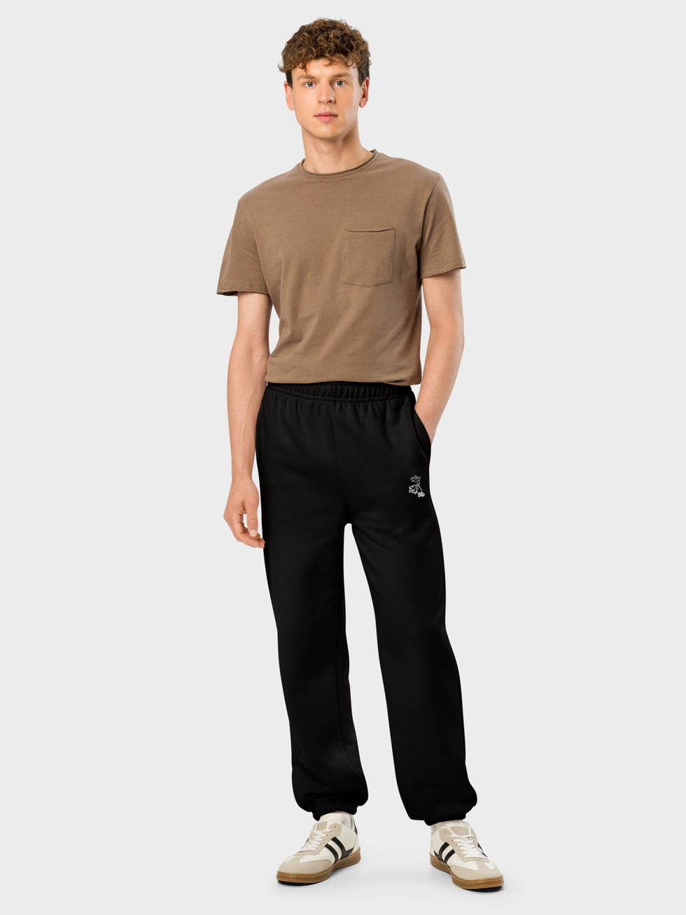 de face, jeune homme en t-shirt marron et jogger en molleton noir brode mascotte frenchborn en blanc sous poche