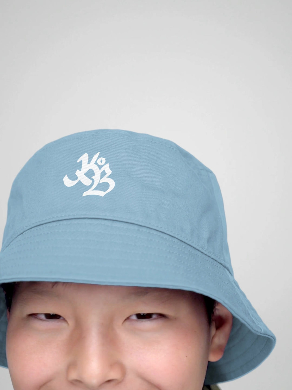 jeune garcon portant un bob de couleur Stone blue brodé en blanc du logo Krew Of Ballers du label FRENCHBORN