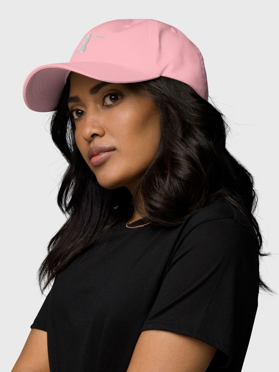 femme brune portant une casquette rose brodée en blanc du logo d'un joueur de basket en action