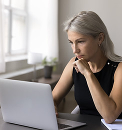 Concentrated mature woman office worker is busy by pc screen read electronic document. Foc