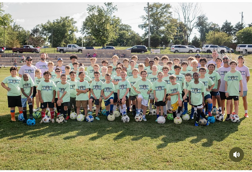 Group photo of boys ages 9–17 at the Nashville youth soccer camp, standing on the field in matching camp shirts with soccer balls at their feet.