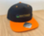 Schwarze WattaBox Snapback Cap mit orangefarbenem Schirm und WATTABOX Logo.