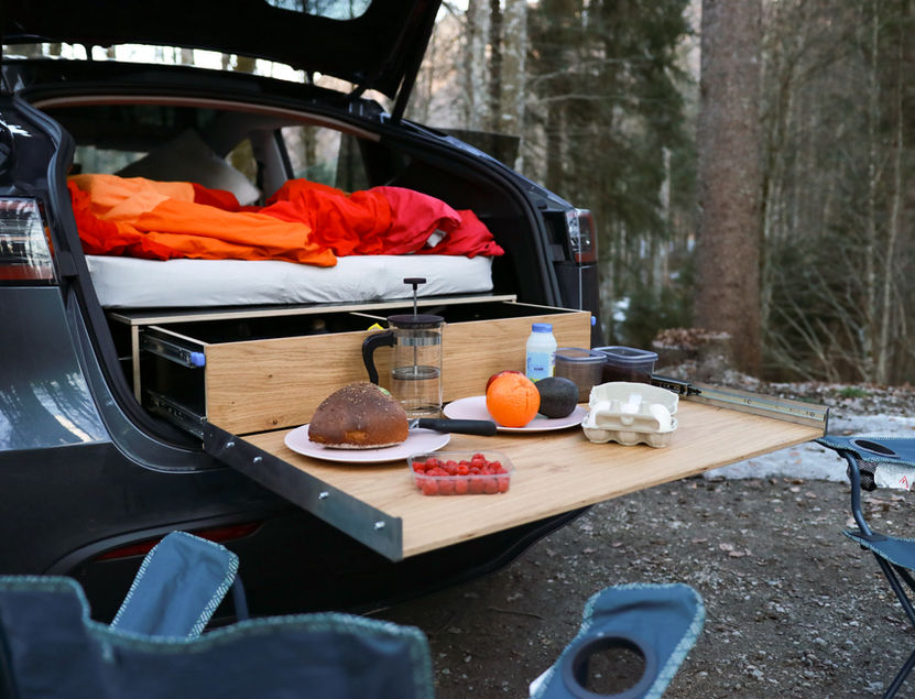 Ein Camping-Setup mit Essen und Ausrüstung im Kofferraum.