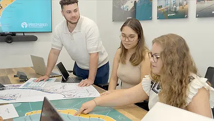 Two women and a man having a meeting, looking over various documents.