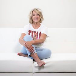 Smiling woman sitting on a white sofa, wearing a t-shirt and jeans