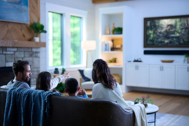 Mother and children watching TV in a bright, cozy living room. Home Entertainment.