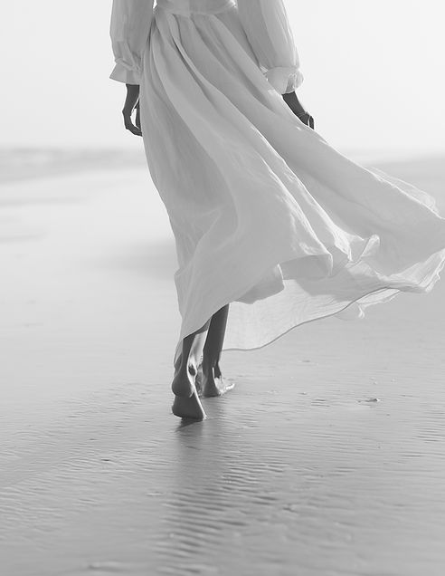 woman walking in sand with flowy white dress