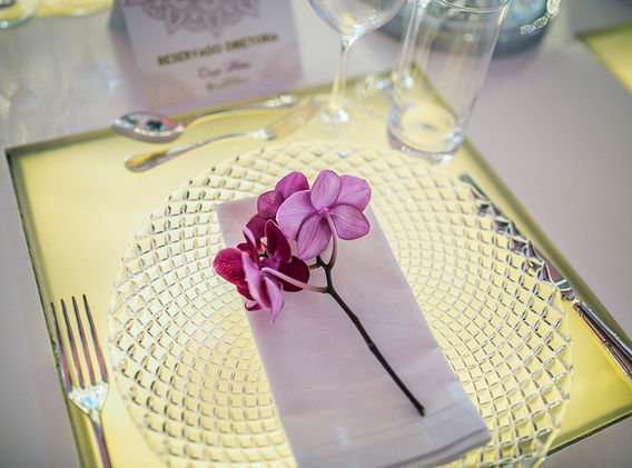 Detalhe da mesa posta mostrando o sousplat transparente e as orquídeas rosa