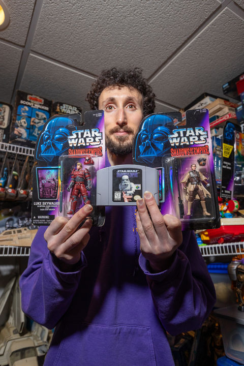 Daniel Chironno holding up a Star Wars N64 game and two action figures. Photo by Moments By Migs.