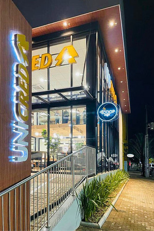 Fachada da agência Unicred Carlos de Carvalho em Cascavel, com o Coopcafé integrado, proporcionando aos cooperados uma experiência única que combina serviços financeiros com um ambiente de café