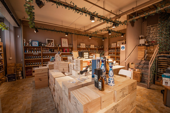 Espace d'accueil et de vente du caviste LA CAVE D'AUBER. Etagères, caisses en bois de vins de Bordeaux, sur lesquelles sont déposées des bouteilles de whisky Chichibu, de téquila Clase Azul, de vins rouges issus de Grands Crus tels que Pétrus en Pomerol et Château Latour en Pauillac. Une centaines de bouteilles de vins et spiritueux sont exposées sur les étagères.