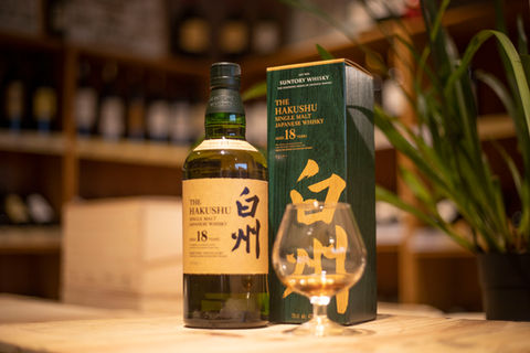 Une rare bouteille de whisky japonais Hakushu 18 ans avec son étui et un verre à pied de dégustation.