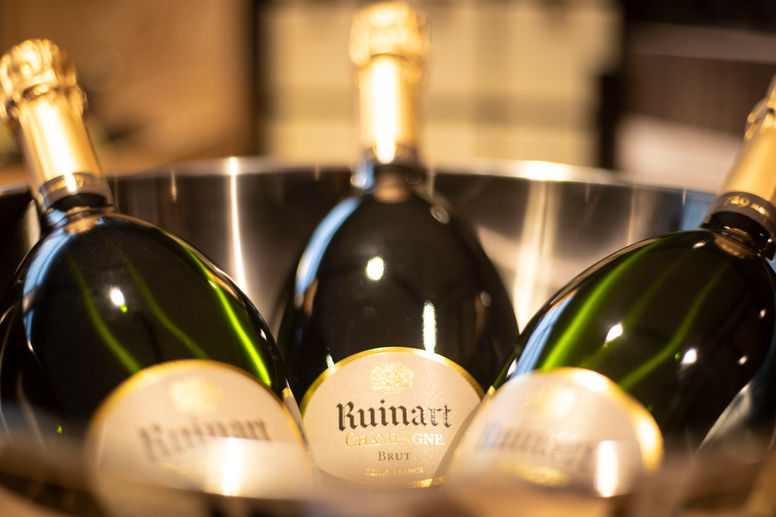 Trois bouteilles de champagne le R de Ruinart Brut dans un sceau à champagne.