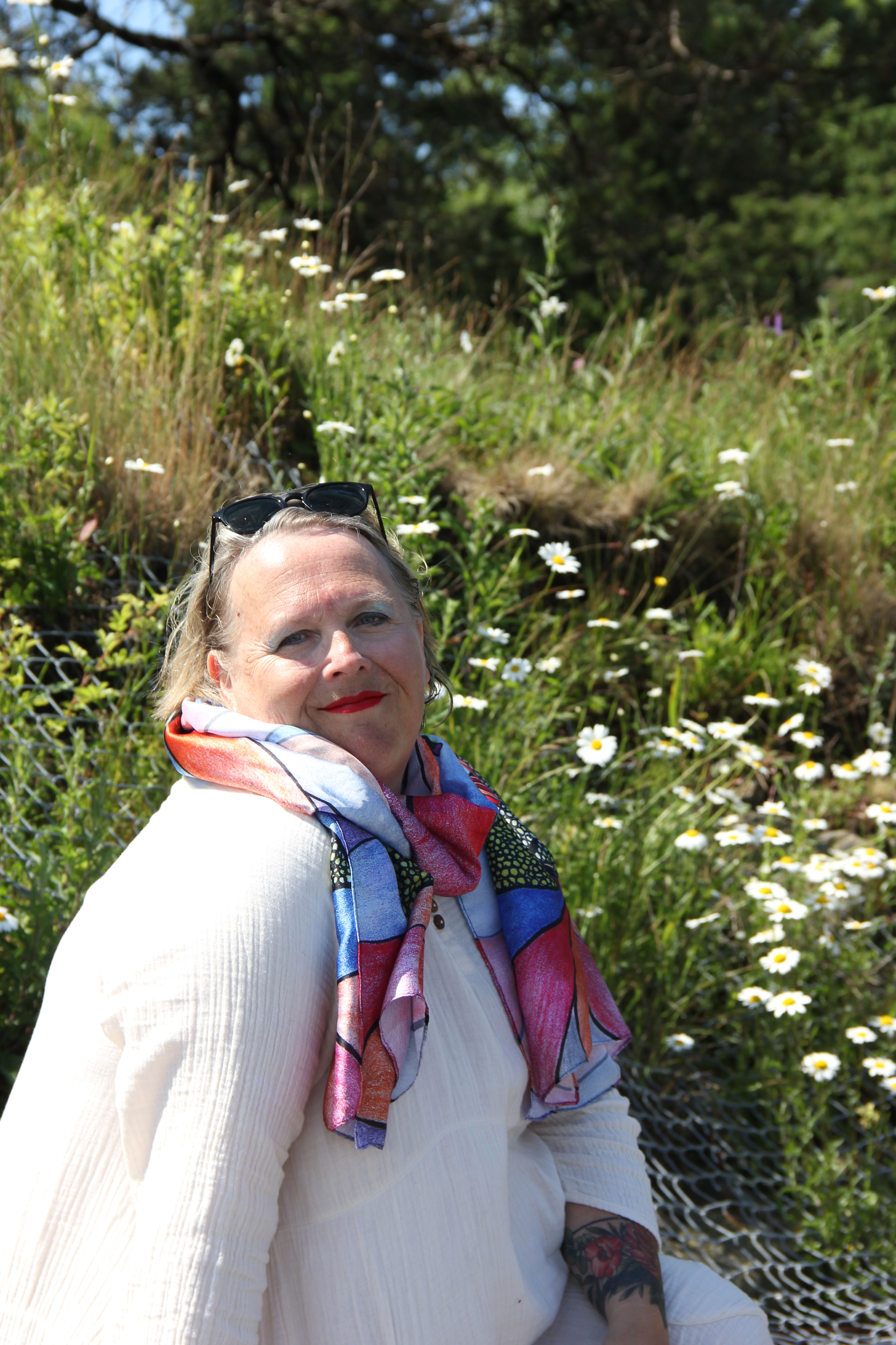 Woman wearing a colorful scarf, smiling among white daisies