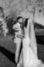 Bride and groom holding each other closely, smiling in an outdoor park setting