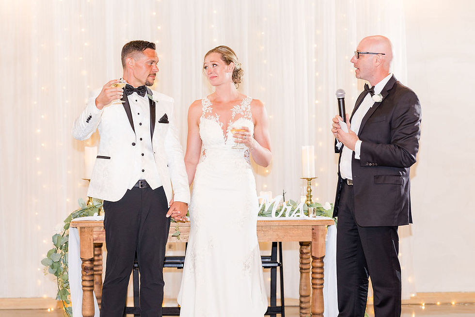 Newlywed couple looks at each other while giving toast at reception.