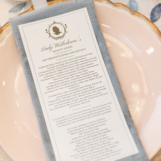 Wedding place setting with a printed menu card on a folded napkin, styled on a blush plate.