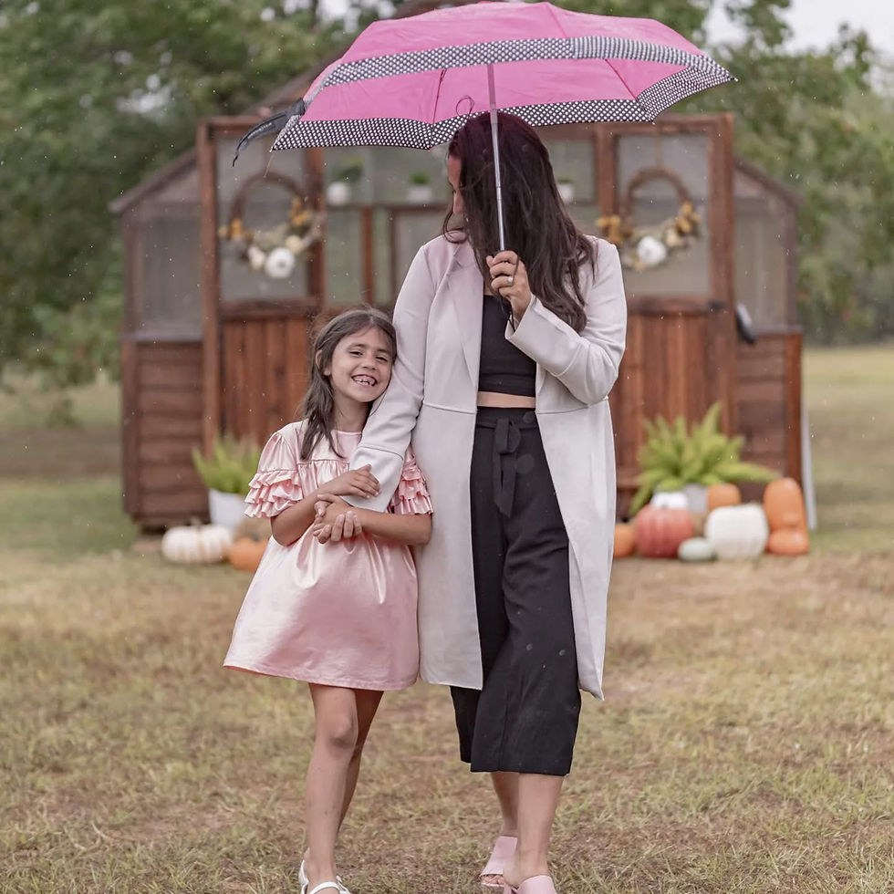 Brandi walking with her daughter outdoors under an umbrella.