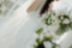Bride in white dress with tulip bouquet, surrounded by flowers, veil flowing in soft light