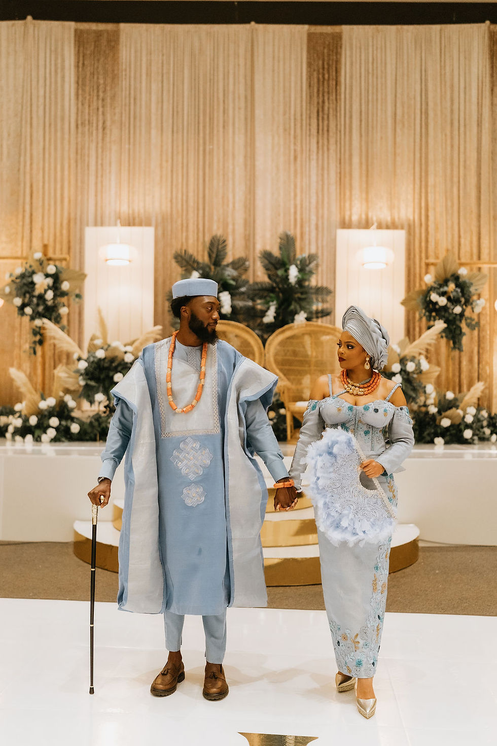 Bride and groom hold hands in stunning blue Nigerian wedding attire