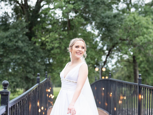 Stress-free bride smiling while standing on a decorated bridge.