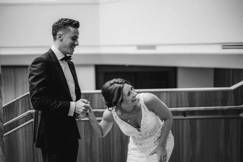 A couple laughs, sharing a first look before the ceremony in an elegant open staircase