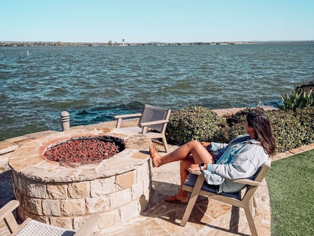 Brandi relaxing by a lakeside fire pit with outdoor chairs overlooking the water in Houston.