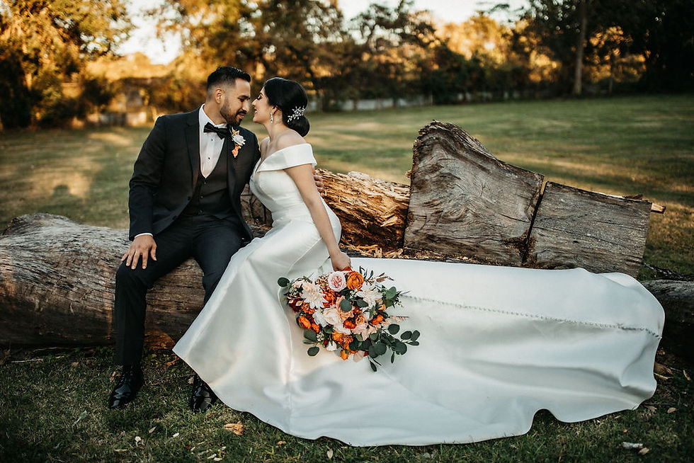 Bride and groom sit on a log during outdoor Houston wedding.