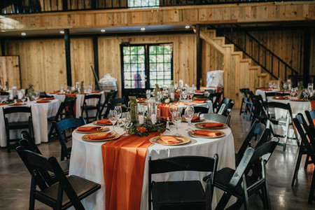 Reception tables with orange runners and gold accents at Houston barn wedding.