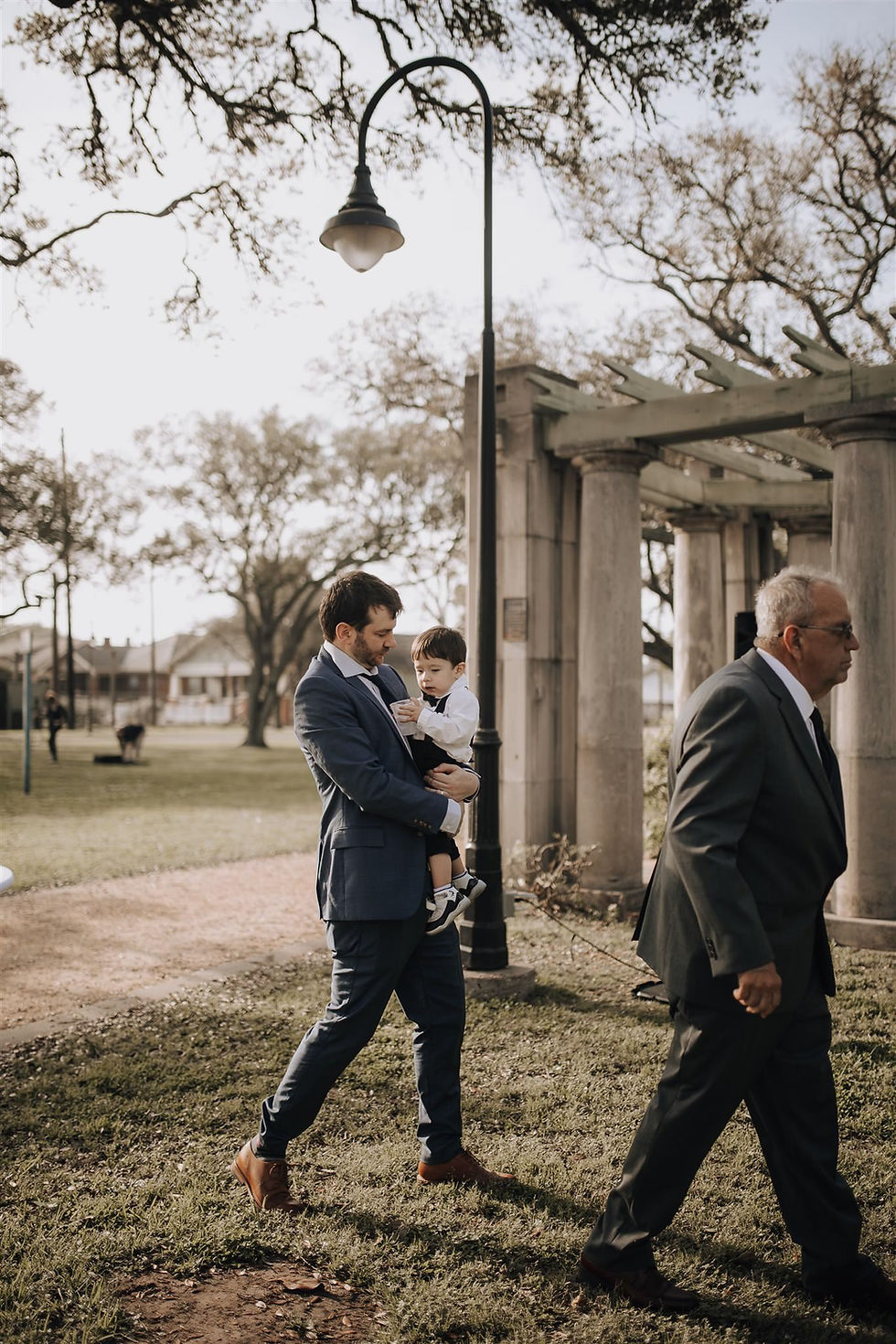 Guest carries child during outdoor Texas wedding.