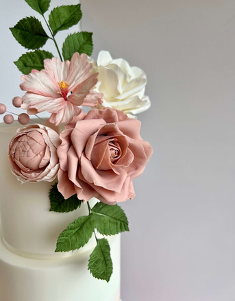 Hand made sugar flowers in blush pink and ivory on the top tier of a wedding cake