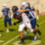Football player Patrick Blackwood being tackled during a game