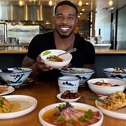 Smiling Patrick Blackwood holding a bowl of food at a restaurant promotion.
