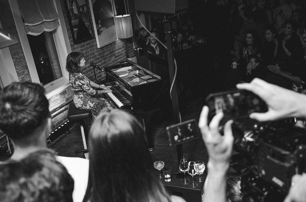 A group of people watching Norah Jones perform on the grand piano, image.
