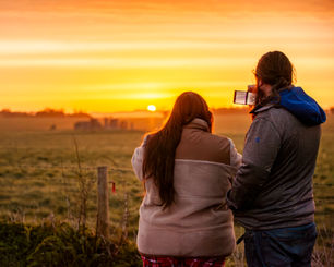 Whit and Nathan taking photo of a sunset over Stonehenge at dawn.