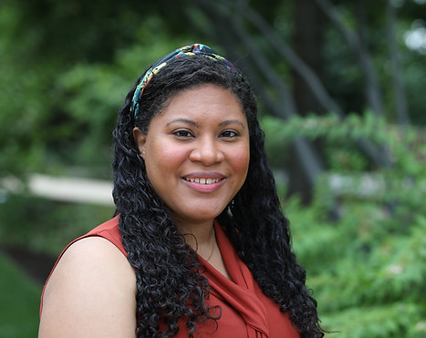 A Disabled Afro-Dominican woman with long curly hair smiling at the camera