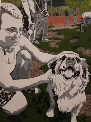 The background is of our community garden including the cob kitchen and people meandering in the background. The foreground depicts a non binary individual with glasses smiling and paired with my dog that is a smiling long haired fluffy mutt. The background is in color, mostly greens and blues with a terracotta colored cob kitchen in the very back. The people and my dog are in black, grey, and white high contrast.
