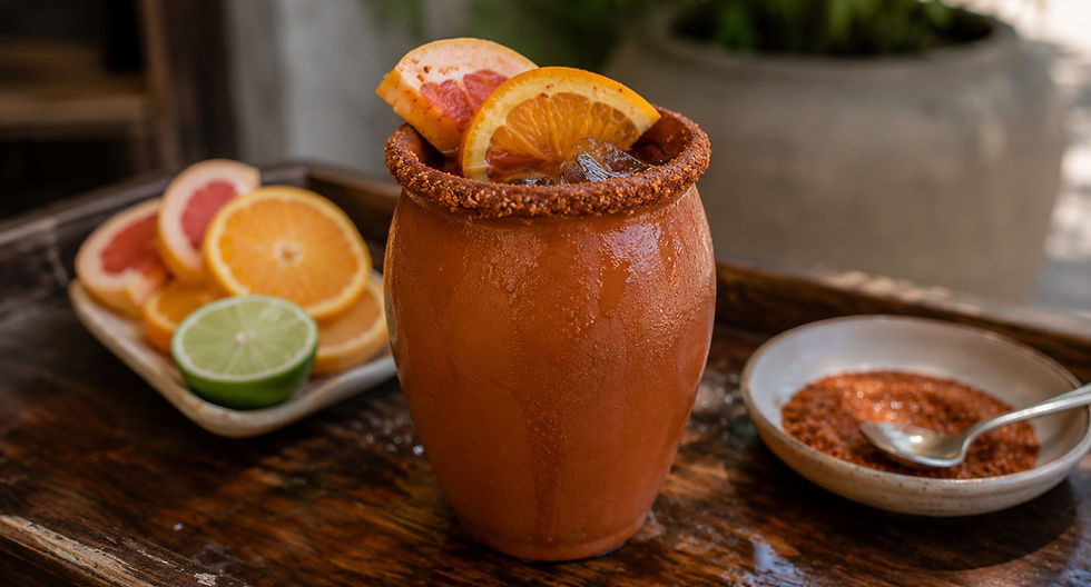 Traditional Mexican cantarito cocktail served in a clay cup with fresh orange, grapefruit, lime, and a chili-salt rim.