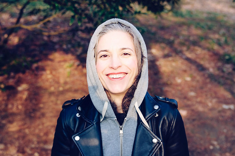 • A healthcare professional exploring the woods stands and smiles at the camera