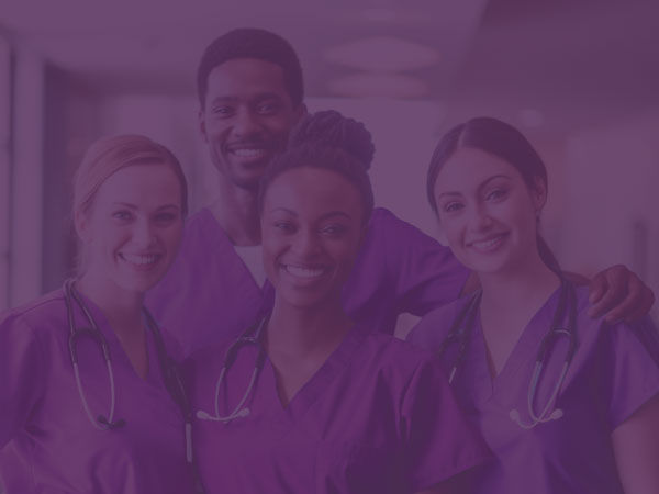 A group of healthcare professionals working at a nursing home smile at the camera.